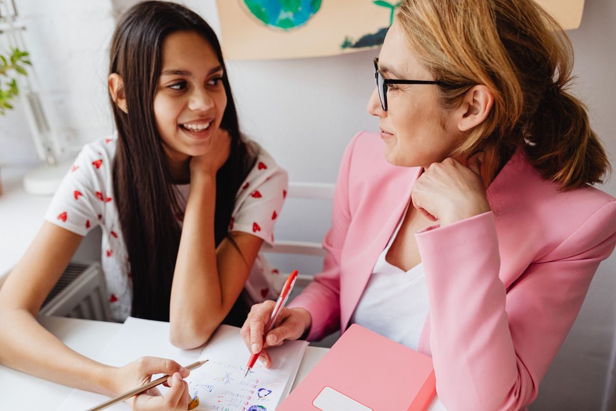 A careers adviser and a smiling student talking through notes together at a desk